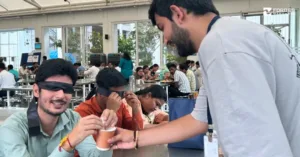 Members wearing blindfolds participate in a multi-sensory activity, experiencing challenges faced by visually impaired individuals while being assisted by a volunteer.