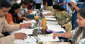 Employees, seated at tables, work on worksheets with coloured pens and markers as part of the volunteering activity for Beyond Business Week.