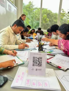 A group of Forbes Marshall members sit around a table, attentively colouring and filling out worksheets with pencils and markers during Beyond Business Week activities.