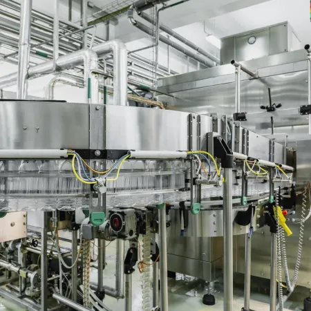 case study thumbnail image showing a conveyor of PET bottles moving into a bottle washing machine inside a beverage plant