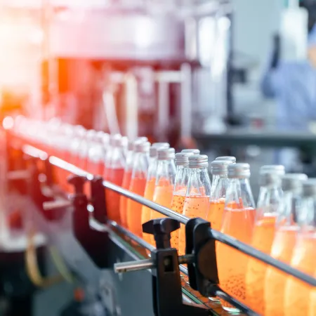 case study thumbnail image: orange colored aerated beverages in glass bottles on a conveyor line in a beverage manufacturing plant
