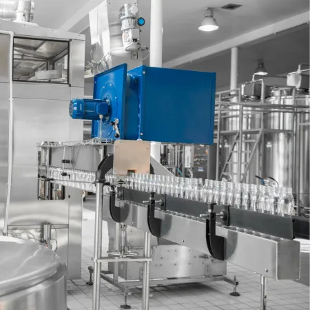 Conveyor of empty bottles heading into a bottle washing machine inside a beverage manufacturing plant