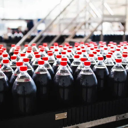 Indonesia cola Rows of cola bottles with red caps on a conveyor belt in a bottling plant.